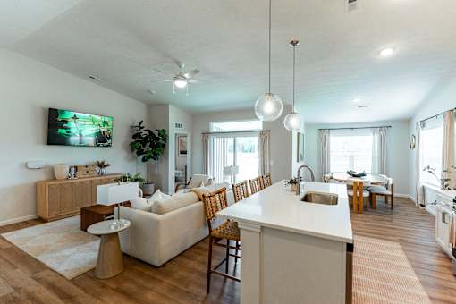 A modern open plan living and kitchen area with a television and a dining table.
