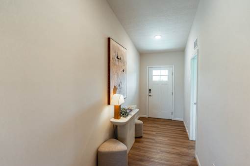 A hallway with a bench and a painting on the wall.