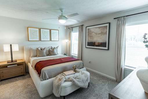 A bedroom with a large bed and a ceiling fan.