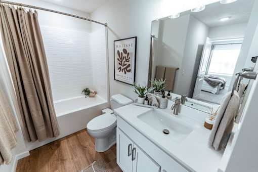 A bathroom with a white sink, toilet, and a brown shower curtain.
