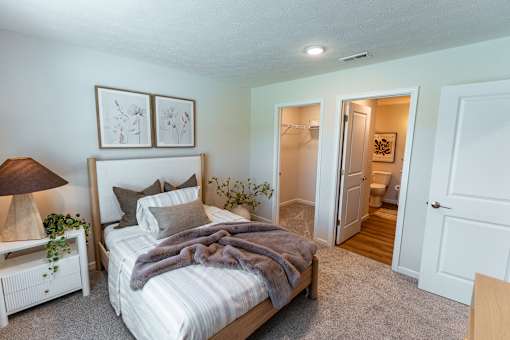 A bedroom with a bed, nightstand, and lamp.