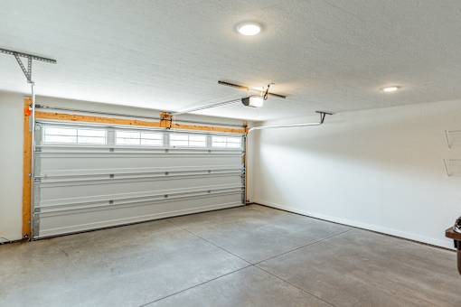 A garage with a white wall and a white ceiling with a fan.
