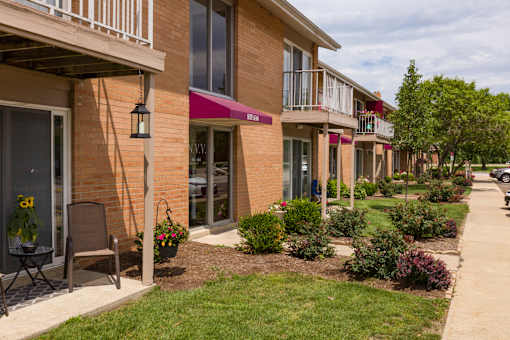 A row of apartment buildings with green bushes in front.
