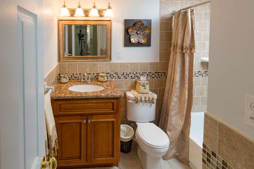 A bathroom with a brown cabinet, a white toilet, and a brown shower curtain.