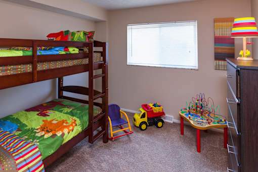 A child's bedroom with bunk beds, a toy truck, and a table with toys.