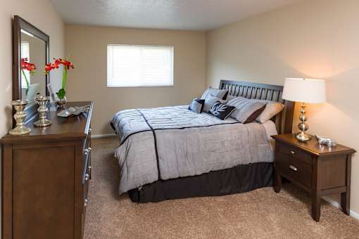 A bedroom with a bed, nightstand, and a dresser.