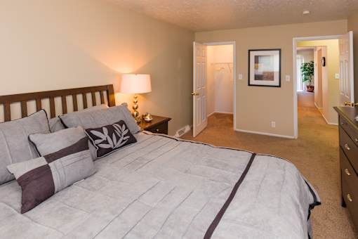 A bedroom with a large bed and a lamp on a side table.