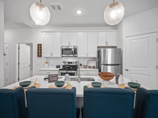 a kitchen with white cabinets and a table with blue chairs