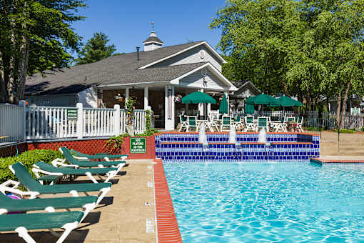 A pool with chairs and a building in the background.