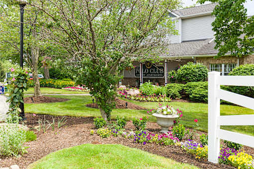 A garden with a white fence and a sign that says "FLO Club".