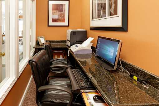 A brown leather chair sits in front of a desk with a computer monitor and keyboard.