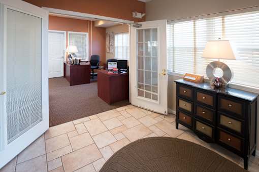 A room with a brown carpet and a brown dresser.