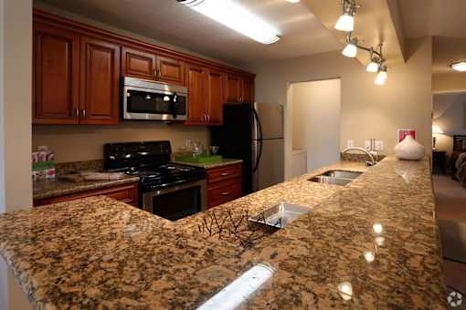 A kitchen with granite countertops and wooden cabinets.