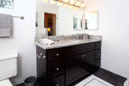 A bathroom with a marble countertop and dark wood cabinets.