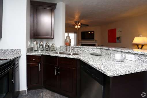 A kitchen with dark brown cabinets and granite countertops.