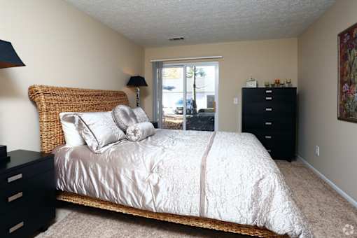 A bedroom with a bed, nightstand, and lamp.