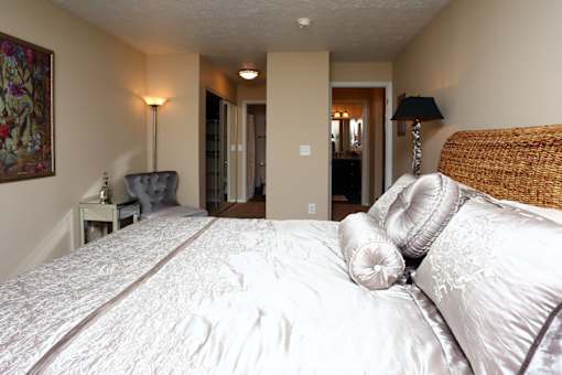 A bedroom with a large bed and a chair.