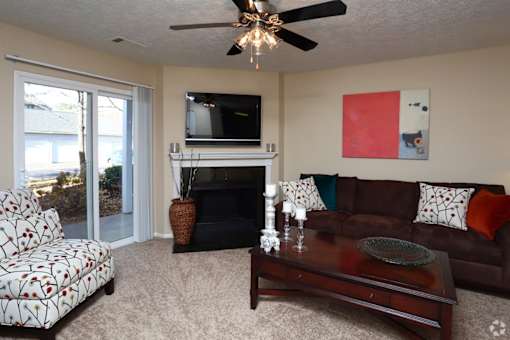 A living room with a fireplace, a couch, a chair, and a painting on the wall.