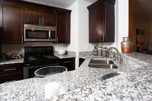 A kitchen with granite countertops and dark wood cabinets.