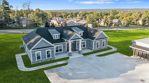 A large house with a grey roof and a driveway in front.