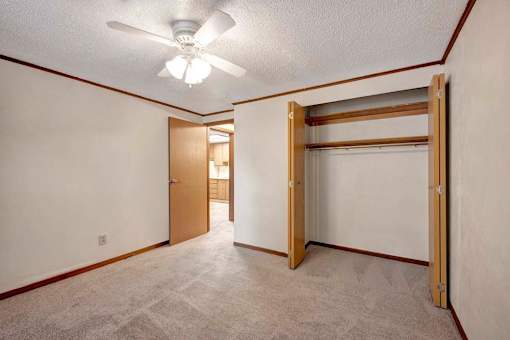 A room with a ceiling fan and a closet with a sliding door.