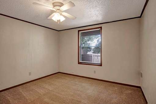 A room with a ceiling fan and a window with a view of a building outside.