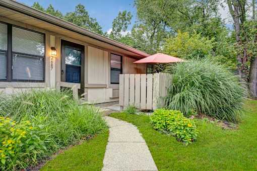A house with a brown roof and a white fence with a garden in front.