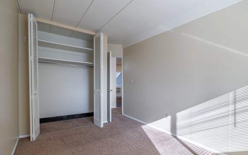 A room with a white wall and a white closet with shelves.