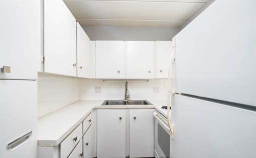 A kitchen with white cabinets and appliances.