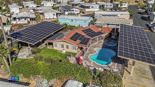 A house with solar panels on the roof and a pool in the backyard.