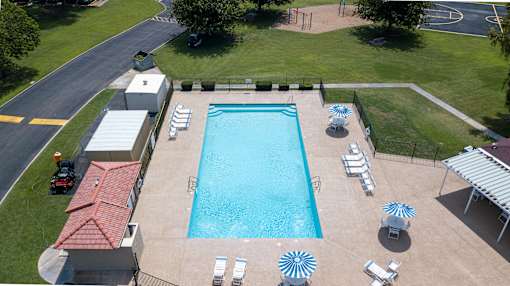 An aerial view of a swimming pool surrounded by sun loungers and umbrellas.