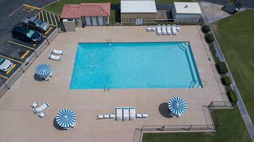 An aerial view of a swimming pool surrounded by sun loungers and umbrellas.