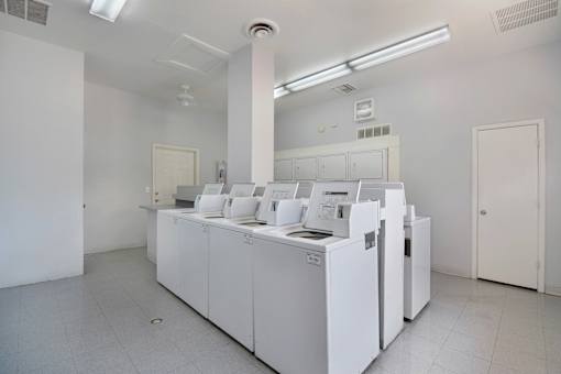 A clean, white room with a row of washing machines.