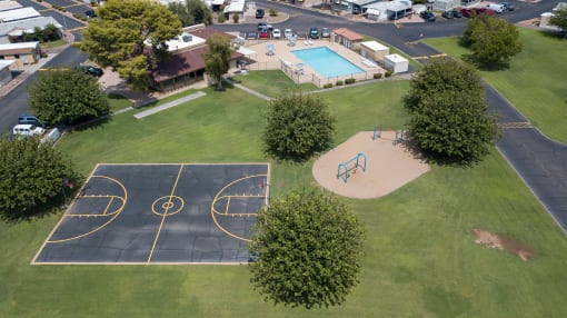 Bird's eye view of Belaire Manor, basketball court, grass area, trees, playground equipment and swimming pool