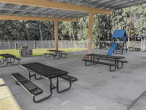 A playground with a slide, picnic tables, and a fence.