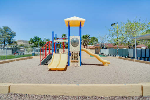 A playground with a yellow slide and a red and blue structure.