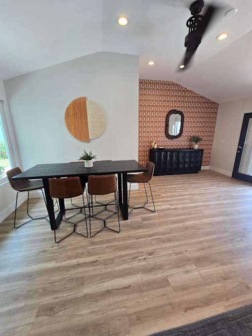 A wooden table with chairs and a small mirror on the wall.