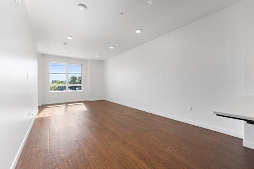 A large empty room with wooden floors and white walls.