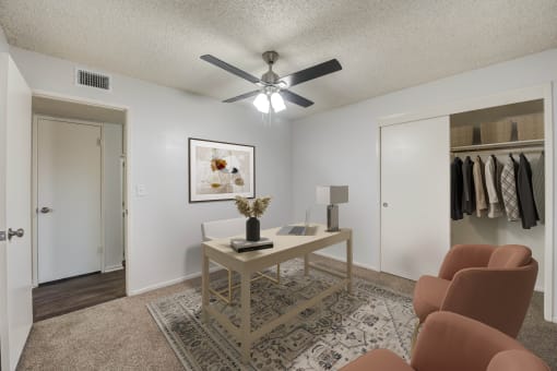 an open living room with a ceiling fan and a closet with clothes hanging