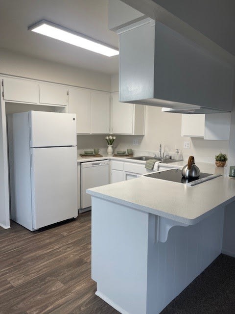 a white kitchen with a sink and a refrigerator