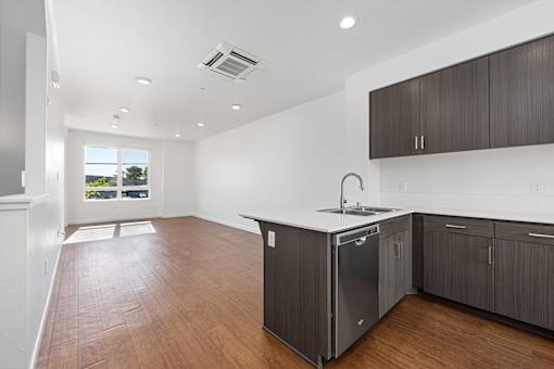A kitchen with dark wood floors and white walls.
