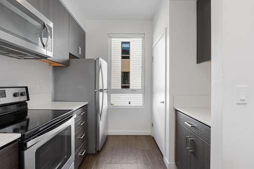 A kitchen with a stainless steel refrigerator and black appliances.
