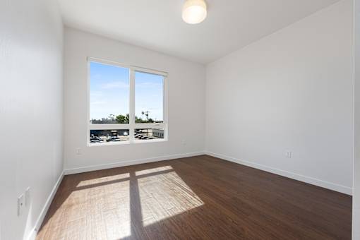 A room with a window overlooking a parking lot.