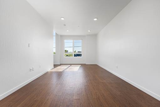 A room with wooden floors and a window overlooking a green landscape.
