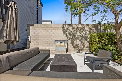 A patio with a couch, table, and umbrella.