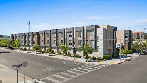 A street view of apartment buildings with a clear blue sky above.