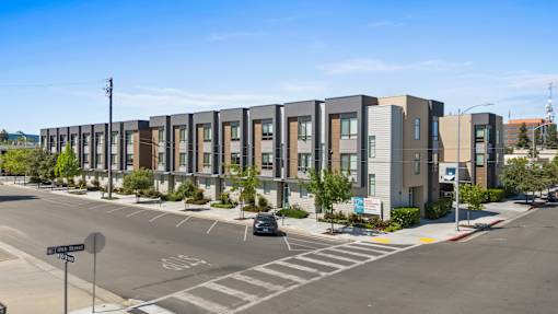 A street view of apartment buildings with a car parked on the side of the road.