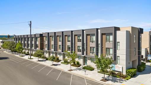 A row of modern townhouses with a clear blue sky above.