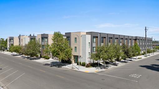 A street view of a row of modern townhouses with a clear blue sky above.