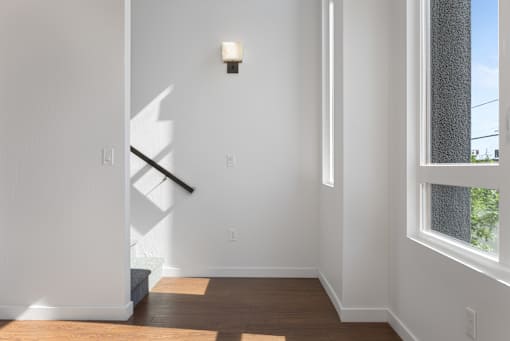 A white hallway with a light on the wall and a window on the right.